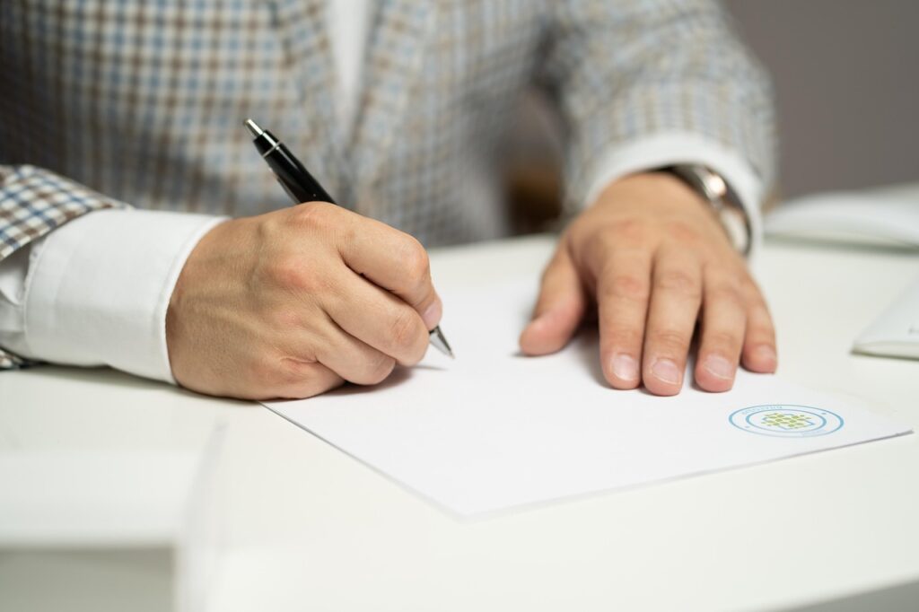 Alt : Un homme remplissant des documents manuellement
