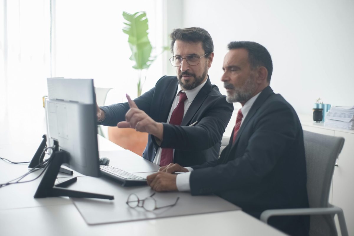A man showing something to his co-worker on a computer