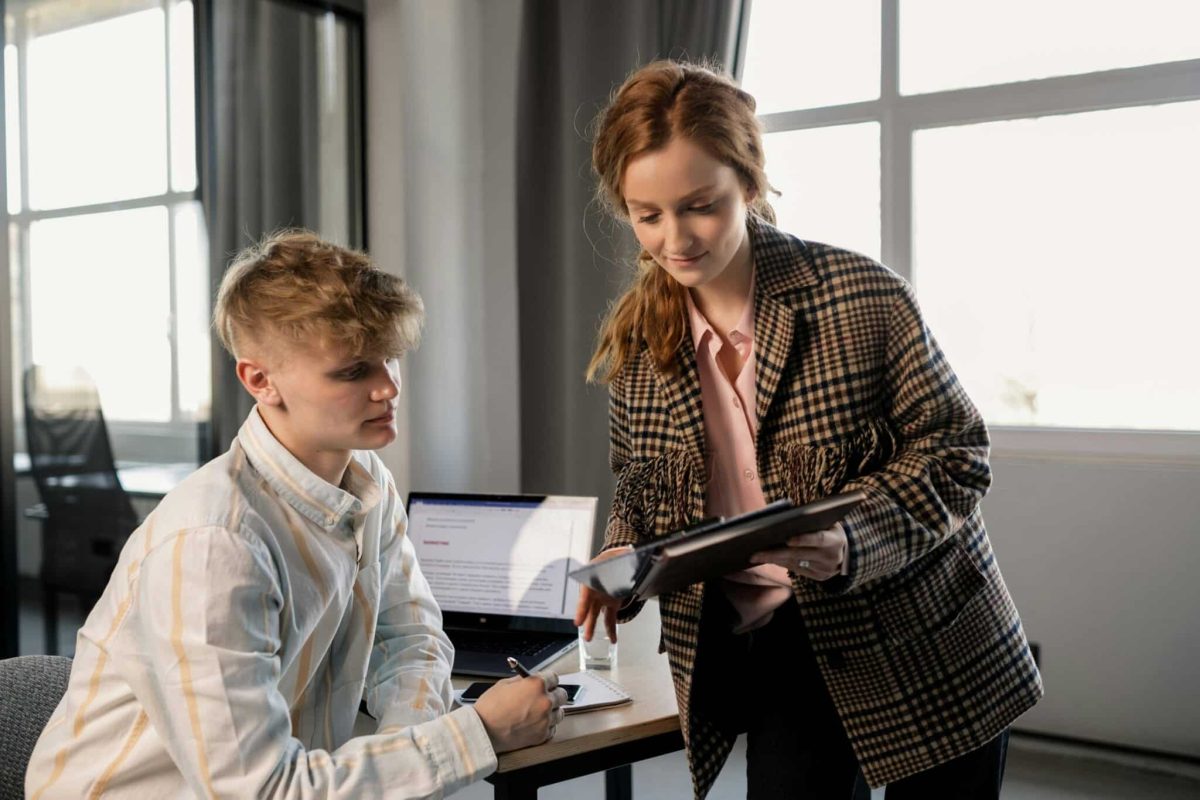 A woman showing something on a laptop to her colleague in an office.